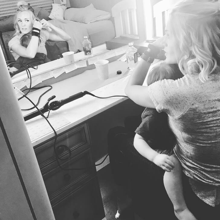 Carrie Underwood cuddles with her child while preparing for a show.